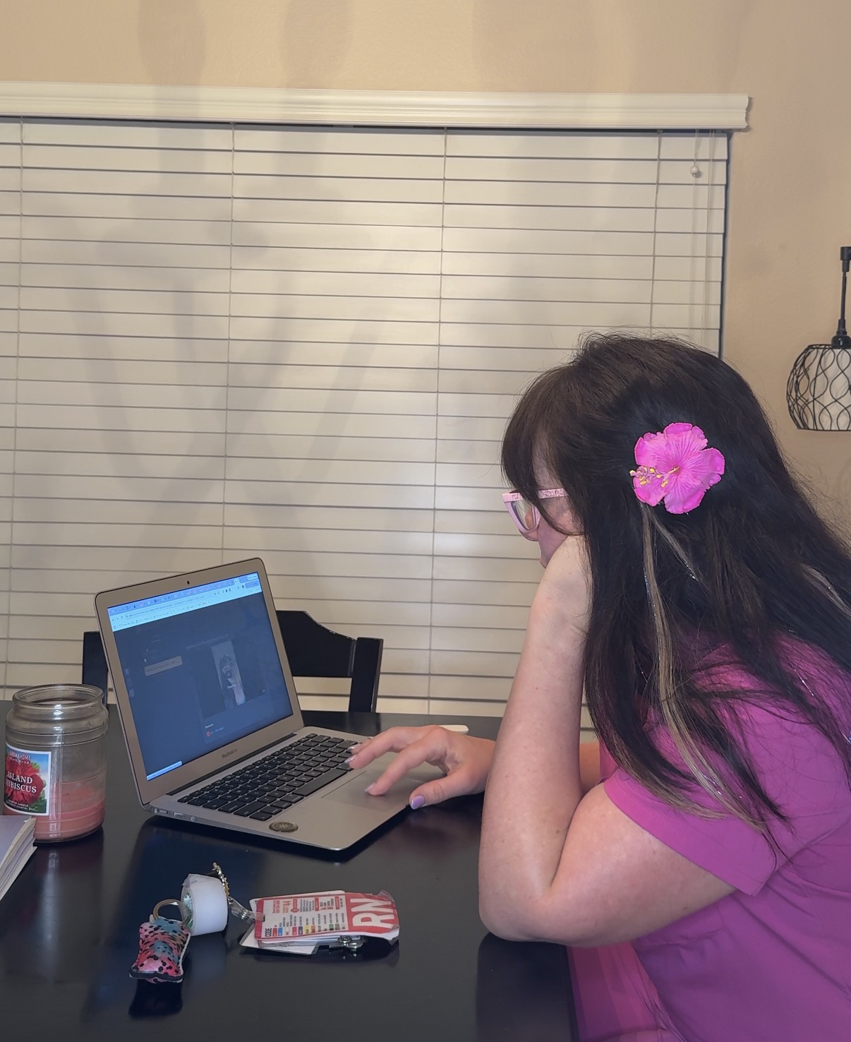 Sherry working at her laptop with her RN badge nearby
